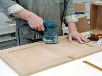 Using a hand sander to smooth parts for a door panel