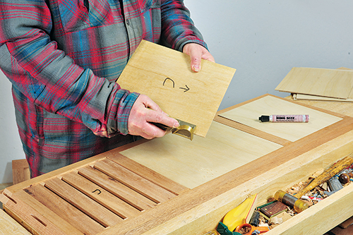 The author uses a small hand plane to trim each 1/8” plywood backing panel for a snug fit in its frame opening. Each is labeled, so it can be returned to the correct frame opening later.